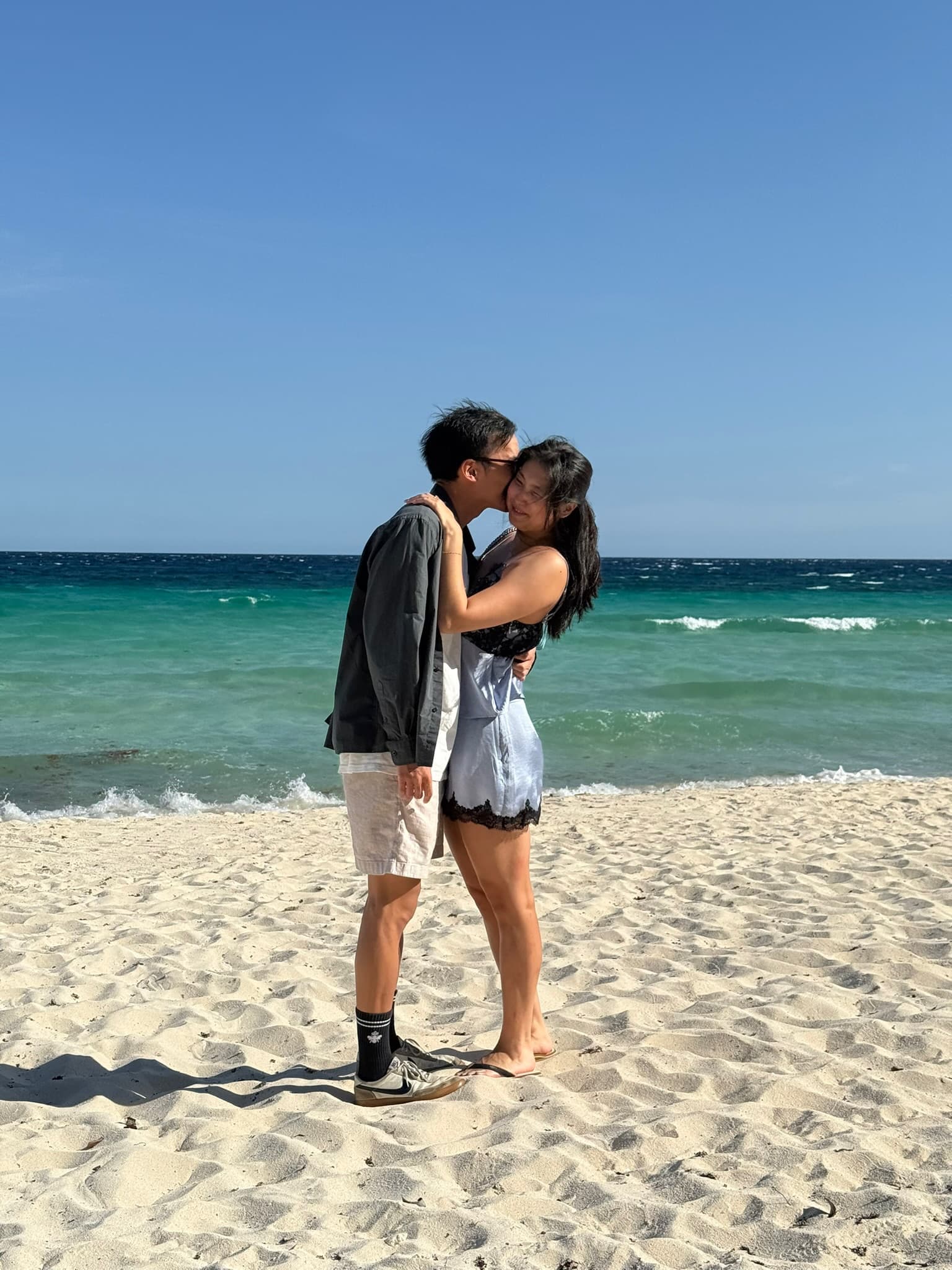 The two of us kissing on the sand, turquoise water behind us.