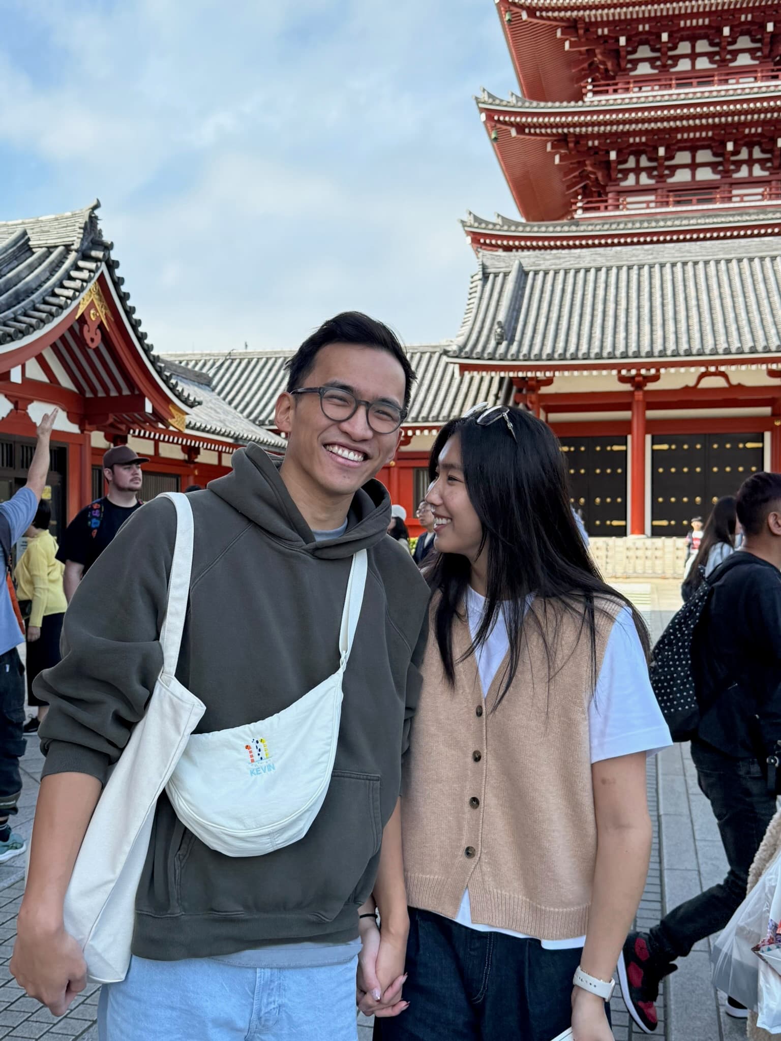 Holding hands in front of a red temple in Japan.