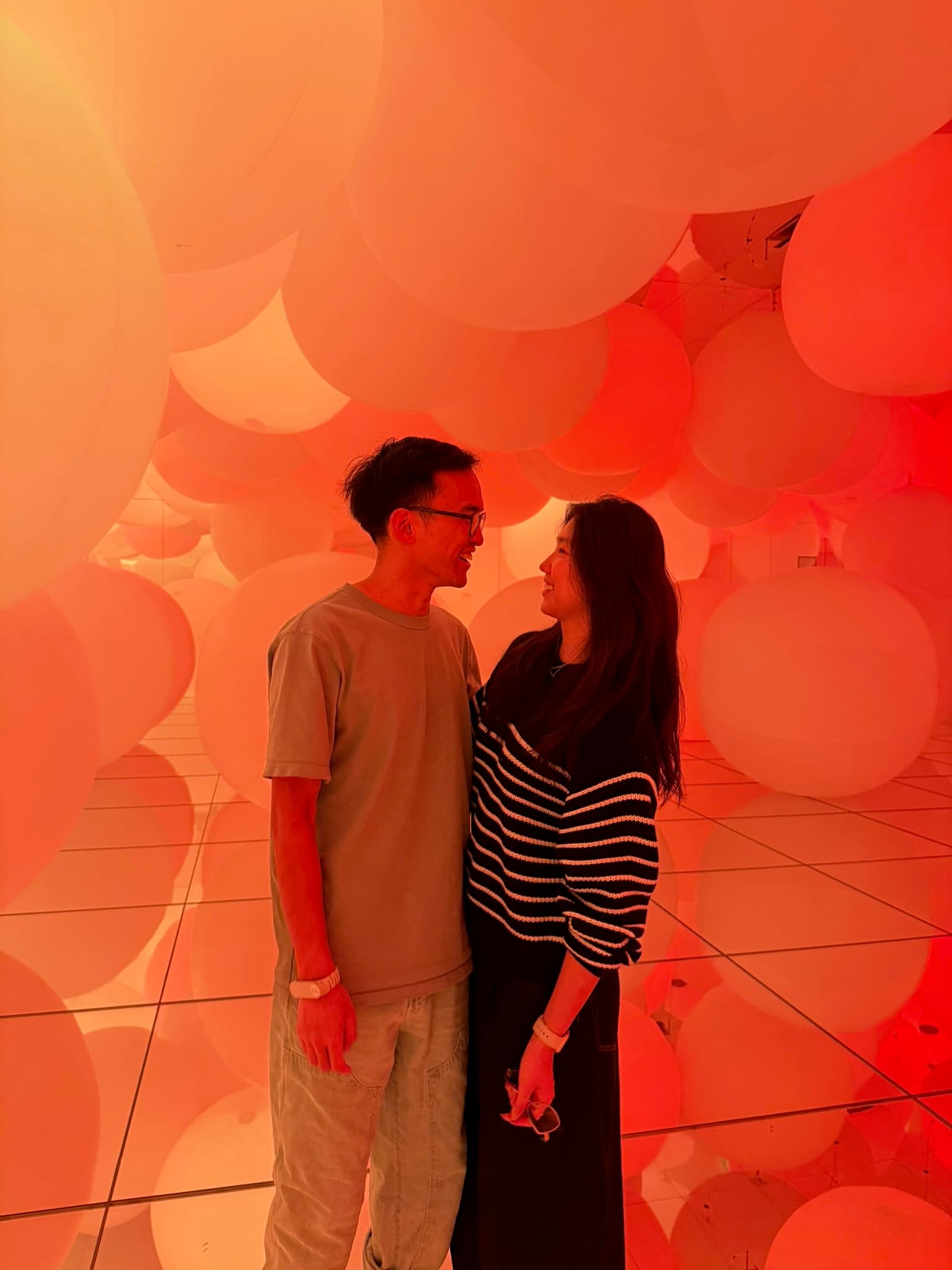 Face to face inside a room of giant glowing spheres, lit orange.