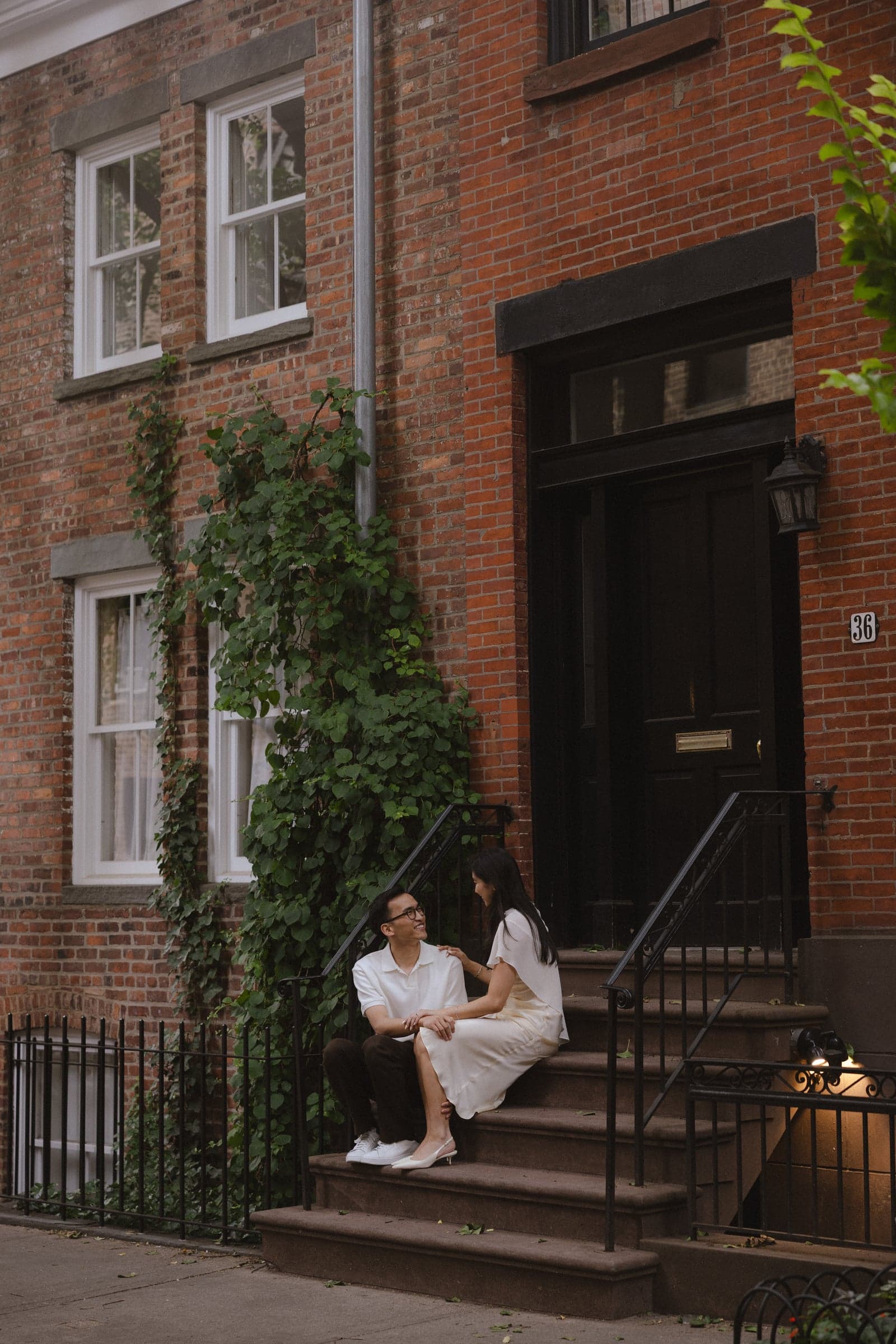 Sitting together on the steps of a brick townhouse, ivy over the window beside us.