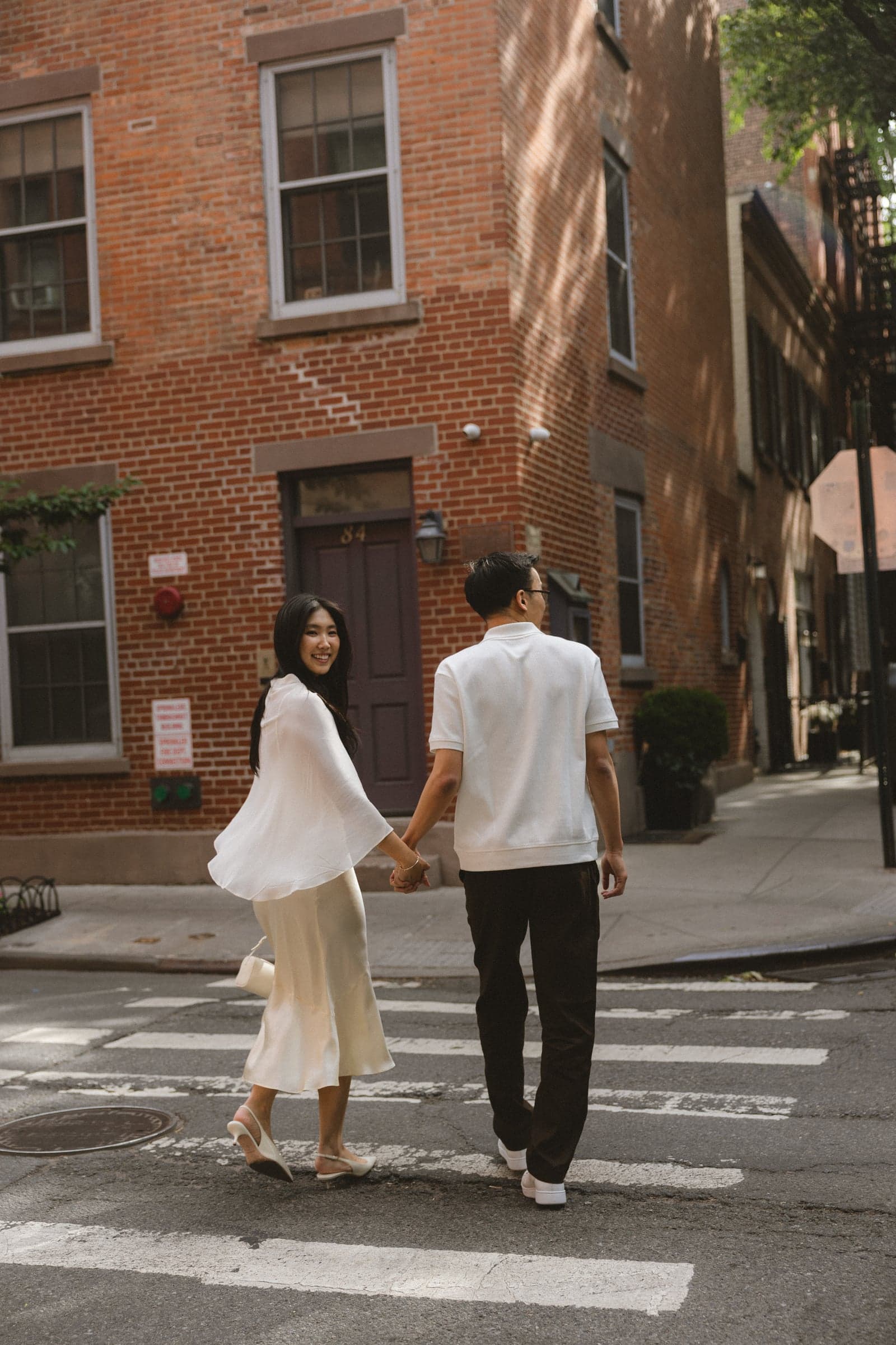 Crossing the street hand in hand, one of us looking back at the camera.