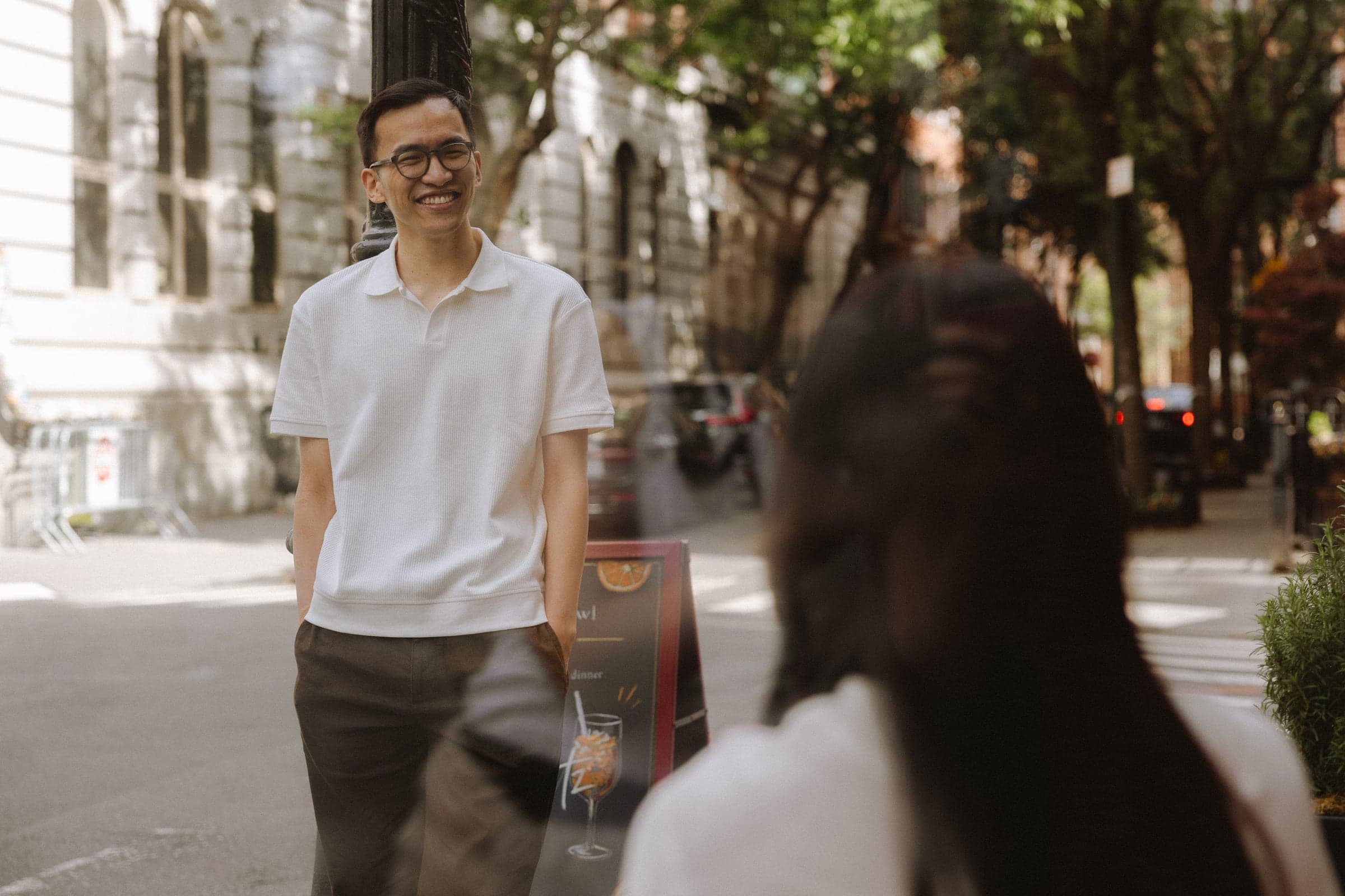 Seen from a cafe table: one of us walking up the sidewalk, grinning, past the other's shoulder.
