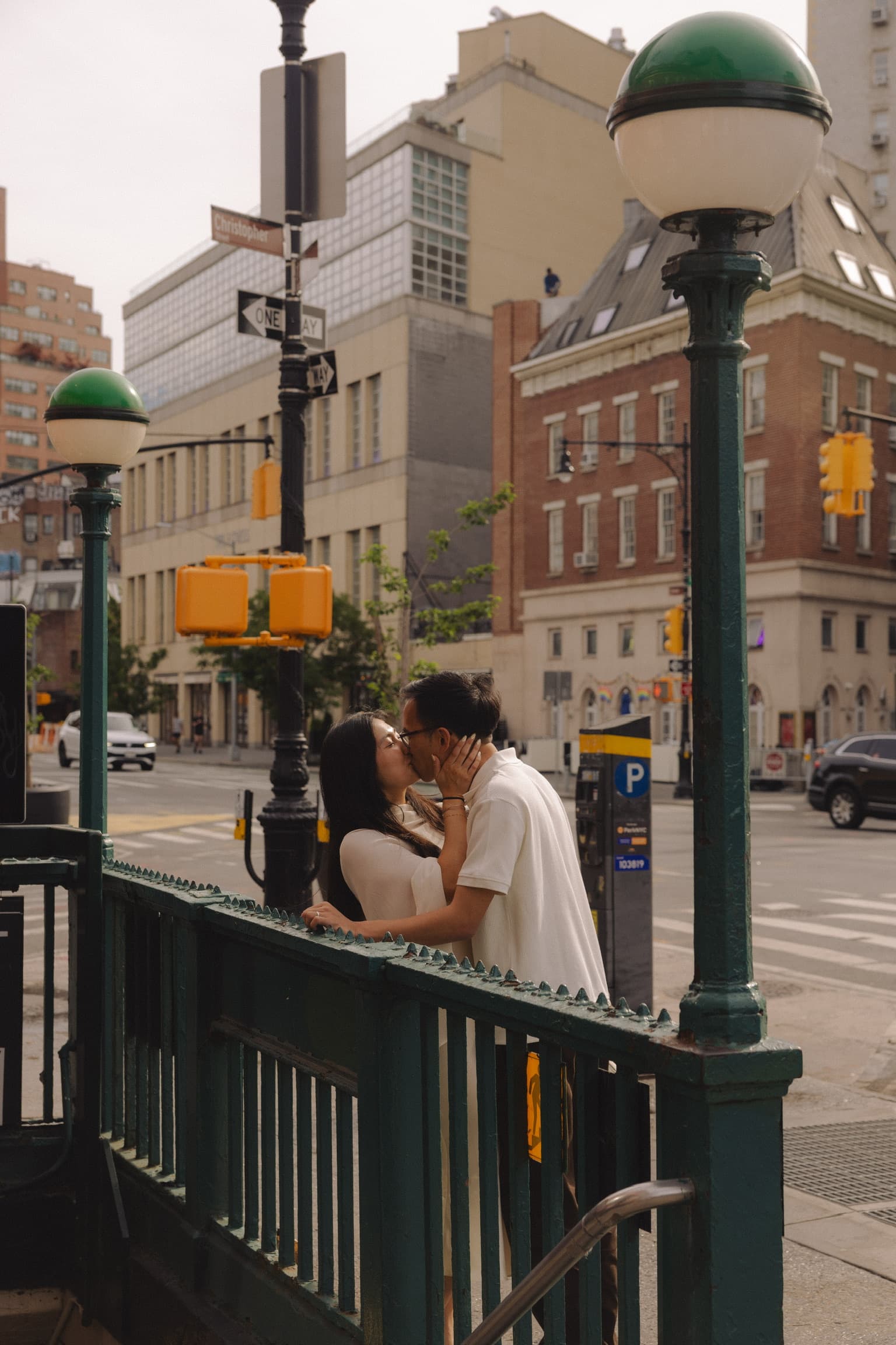 Kissing at the top of a subway entrance on a New York street corner.
